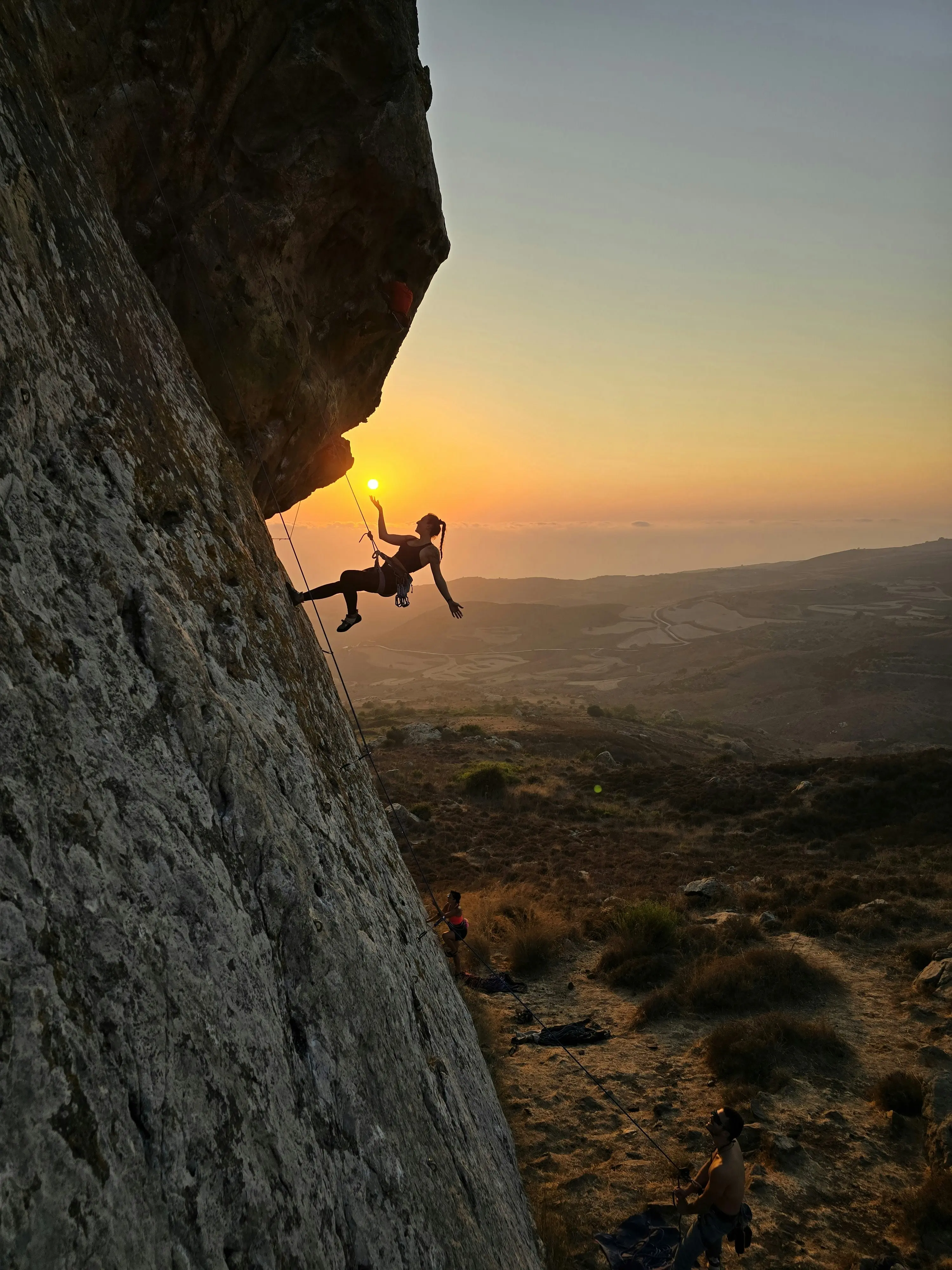 Grimpeuse progressant sur une paroi au coucher du soleil
